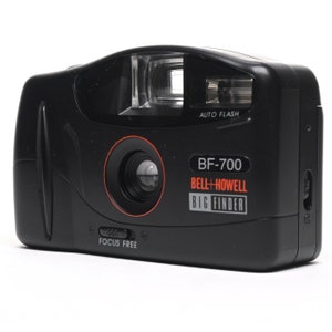 Pode incluir: Uma c&acirc;mera preta Bell + Howell BF-700 com um r&oacute;tulo vermelho "BIG FINDER". A c&acirc;mera tem um flash embutido e uma lente de foco autom&aacute;tico.