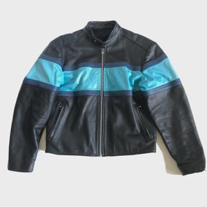 May include: Black leather jacket with a stand-up collar and a full-length zipper. The jacket features a horizontal light blue stripe across the chest and upper arms, with a darker blue stripe above and below. Two zippered pockets are on the front.