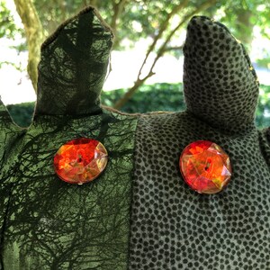 Peut inclure: Gros plan sur un jouet en peluche avec un tissu &agrave; motifs verts et bruns. Le jouet a deux gros boutons de gemmes rouges pour les yeux.