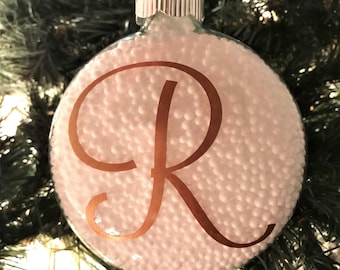 May include: A clear glass Christmas ornament filled with white styrofoam beads and a gold letter "R" decal.