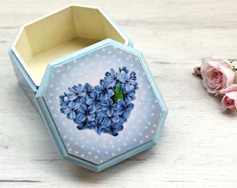 Puede incluir: Una caja de madera azul claro con un diseño en forma de corazón de flores azules en la tapa. La caja está decorada con lunares blancos. La caja está abierta y el interior está vacío.