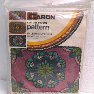May include: A sealed package containing a Caron latch hook pattern. The pattern is titled "Kaleidoscope" and features a floral design in shades of pink, green, and blue. The finished size is 20 x 27 inches. The package text says "easy-to-do, easy-care and simply beautiful."