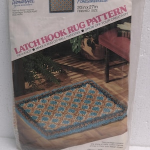 May include: A packaged latch hook rug pattern kit, featuring a finished rug design. The kit includes a canvas printed with a design, measuring 20 x 27 inches. The design is a geometric pattern in shades of blue, brown, and teal. The package reads "Fontainebleau".