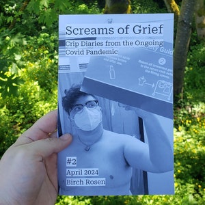 May include: A black and white photograph of a person wearing a face mask holding a book titled "Screams of Grief: Crip Diaries from the Ongoing Covid Pandemic #2 April 2024 Birch Rosen".