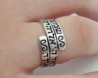 May include: A silver ring with Hebrew text wrapped around the band.