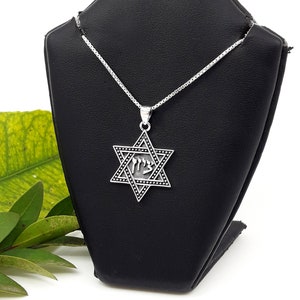 Puede incluir: Un collar de cadena de plata con un colgante de plata de la Estrella de David. El colgante tiene un dise&ntilde;o de esmalte negro y la palabra hebrea "Chai" inscrita en su interior.