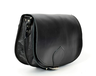 May include: A black leather satchel bag with a flap closure and a buckle. The bag has a rounded shape and a single strap.