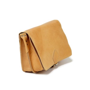 May include: A tan leather satchel bag with a flap closure and a buckle. The bag has a strap that can be adjusted to fit comfortably on the shoulder.