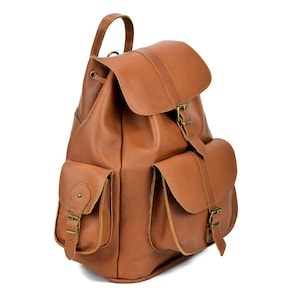 May include: A brown leather backpack with two large front pockets and a buckle closure. The backpack has a drawstring closure at the top and adjustable straps.