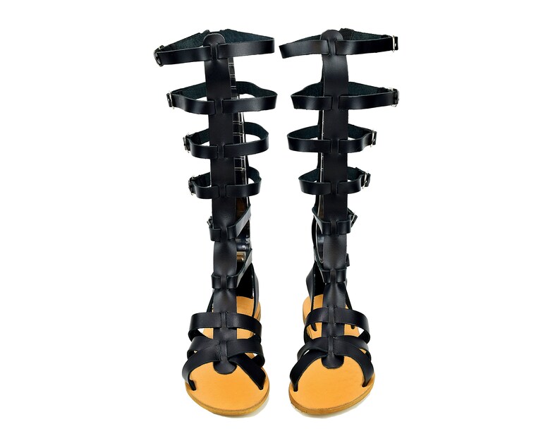 Peut inclure: Une paire de sandales gladiateur en cuir noir avec plusieurs lani&egrave;res et boucles. Les sandales ont une semelle en cuir marron et une pointe ferm&eacute;e.