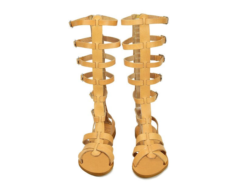 Peut inclure: Une paire de sandales gladiateur en cuir beige avec plusieurs lani&egrave;res et boucles. Les sandales ont une pointe ferm&eacute;e et un talon haut.