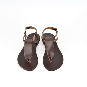 May include: A pair of brown leather sandals with ankle straps. The sandals have a simple design and are made of high-quality leather.