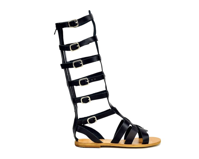 Peut inclure: Sandales gladiateur en cuir noir avec plusieurs lani&egrave;res et boucles. Les sandales ont une semelle en cuir marron.