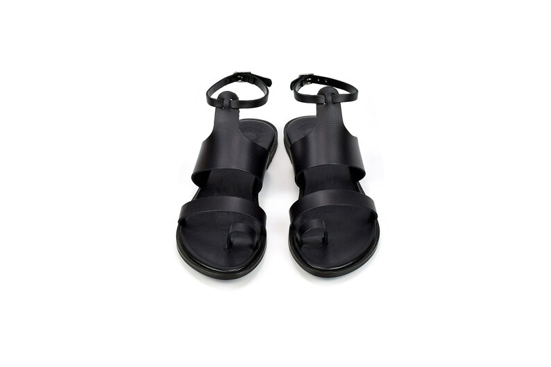 May include: A pair of black leather sandals with ankle straps and toe loops.