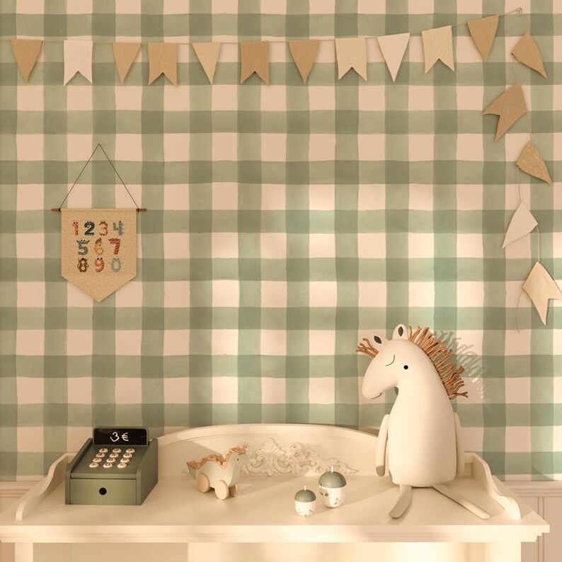 May include: A white wooden table with a green and white gingham wallpaper background. A green cash register, a wooden toy horse, and two small white ceramic eggs are on the table. A beige banner with numbers 1-10 hangs on the wall.