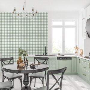May include: A kitchen dining area with a black table and chairs. The wall behind the table is covered in green and white gingham wallpaper. The kitchen has green cabinets and a white countertop.