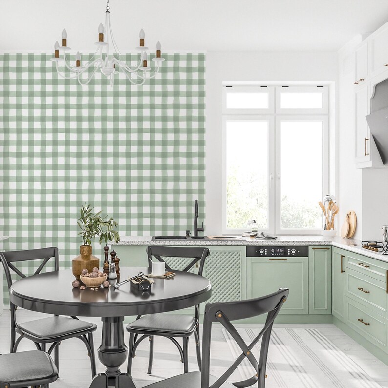 May include: A kitchen dining area with a black table and chairs. The wall behind the table is covered in green and white gingham wallpaper. The kitchen has green cabinets and a white countertop.