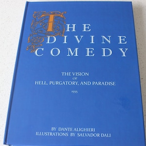 May include: A blue hardback book titled "The Divine Comedy: The Vision of Hell, Purgatory, and Paradise" by Dante Alighieri with illustrations by Salvador Dali.