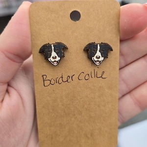 May include: A pair of wooden earrings featuring a black and white border collie dog design. The earrings are on a brown card with the text "Border Collie" written in black.