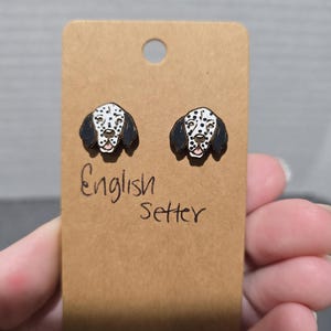 May include: A pair of wooden earrings featuring a black and white English Setter dog design. The earrings are on a brown card with the text "English Setter" written in black.