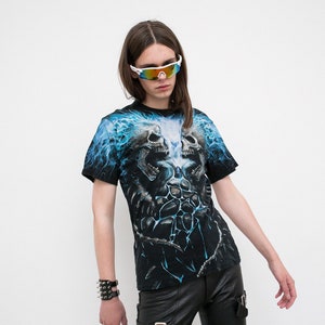 May include: A black t-shirt with a blue and white graphic print of two skulls with flames. The person wearing the shirt is wearing black leather pants and sunglasses.
