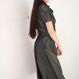 May include: A woman wearing a dark green, textured, short-sleeved dress with a button-up front.
