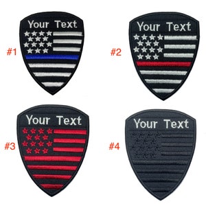 May include: Four embroidered patches in the shape of a shield with the text "Your Text" at the top. The patches feature different variations of the American flag with a blue line, red line, red stars, and black stars.