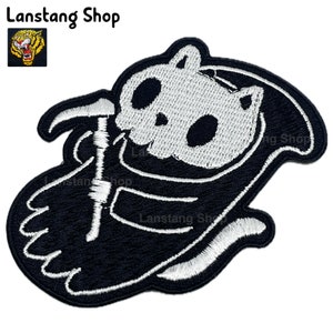 May include: Black and white embroidered iron-on patch of a cat skeleton wearing a hooded robe and holding a scythe. The cat's skull is visible and the robe is outlined in white.
