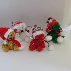 May include: Four knitted teddy bears wearing Santa hats with jingle bells. The bears are red, white, green, and yellow.