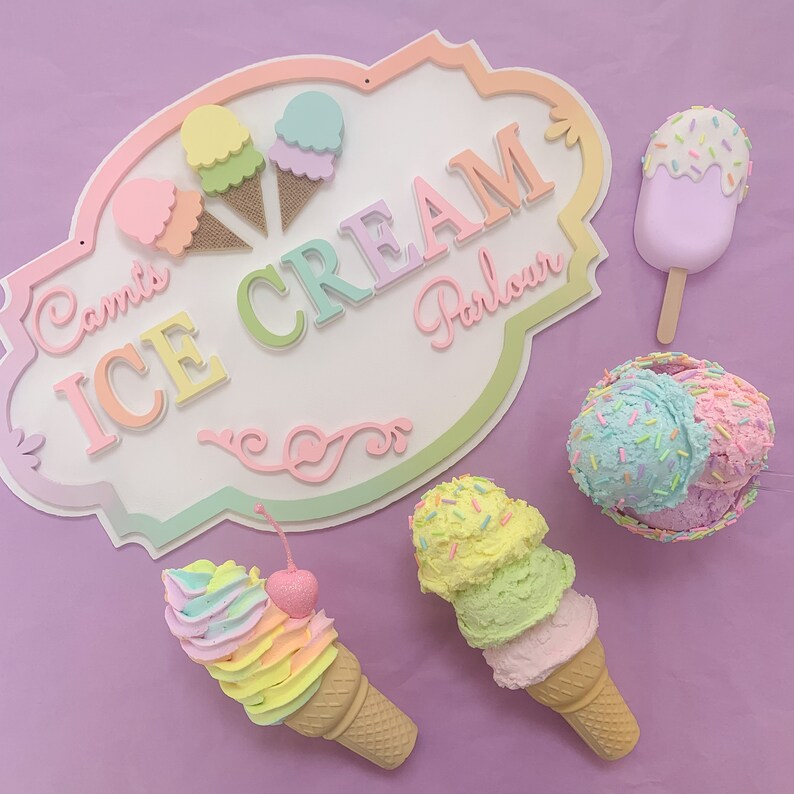 May include: A pastel-colored wooden sign that reads "Camis Ice Cream Parlour" with various pastel-colored ice cream cones and a popsicle.