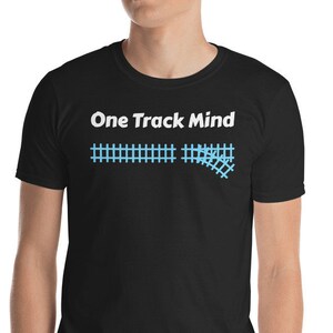Può includere: Maglietta nera con testo bianco che recita "One Track Mind" e una grafica blu di un binario del treno.