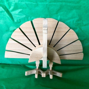 Op de afbeelding: Een houten kalkoenfiguur met een waaiervormige staart en een gedetailleerd hoofd en poten. De kalkoen is gemaakt van lichtbruin hout en heeft een natuurlijke afwerking.