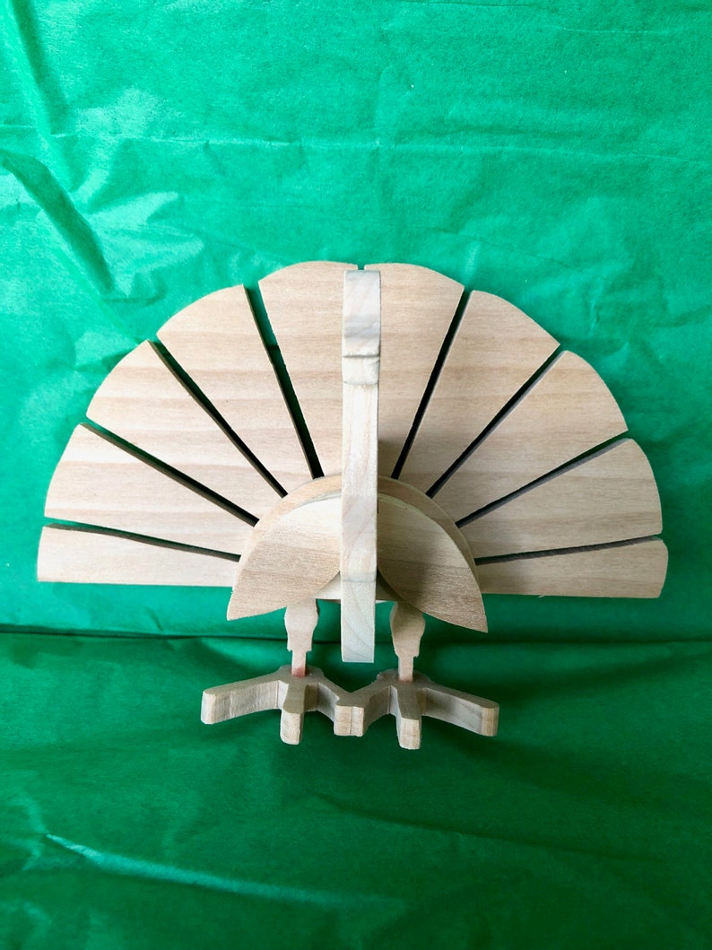Op de afbeelding: Een houten kalkoenfiguur met een waaiervormige staart en een gedetailleerd hoofd en poten. De kalkoen is gemaakt van lichtbruin hout en heeft een natuurlijke afwerking.