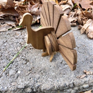 Op de afbeelding: Een houten kalkoenfiguur met een bruine afwerking. De kalkoen heeft een gedetailleerde waaiervormige staart en een gesneden kop.