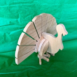 Op de afbeelding: Een houten kalkoenfiguur met een bruine afwerking. De kalkoen heeft een grote waaiervormige staart en een gedetailleerd hoofd en lichaam.