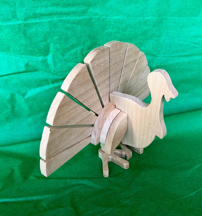 Op de afbeelding: Een houten kalkoenfiguur met een bruine afwerking. De kalkoen heeft een grote waaiervormige staart en een gedetailleerd hoofd en lichaam.