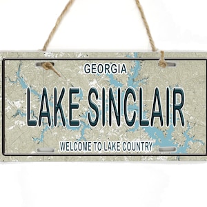 May include: A vintage-style metal sign with a map of Lake Sinclair, Georgia. The sign reads "Lake Sinclair, Welcome to Lake Country".