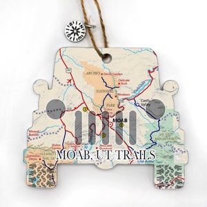 May include: A wooden Jeep ornament with a map of Moab, Utah, and the text "MOAB, UT TRAILS". The map shows the location of Arches National Park, La Sal Mountains, and other points of interest.