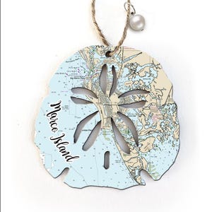 May include: A white sand dollar ornament with a nautical map of Marco Island, Florida. The ornament is made of wood and has a string for hanging.