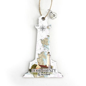 May include: White wooden lighthouse ornament with a nautical map design and a compass charm. The ornament features the text "DOOR COUNTY Wisconsin".