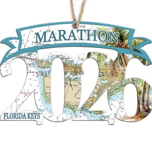 May include: A Marathon Florida Keys ornament with the year 2026 cut out. The ornament features a map design with palm trees and the text "MARATHON" in a banner. It hangs from a natural twine.