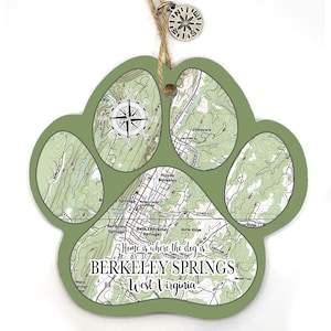 May include: Green paw print shaped wooden ornament with a map of Berkeley Springs, West Virginia. The ornament includes the text "Home is where the dog is... Berkeley Springs, West Virginia".