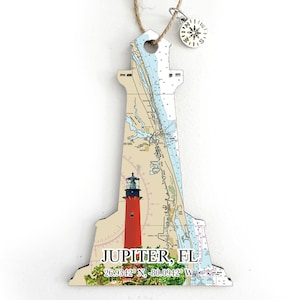 May include: A wooden lighthouse ornament with a nautical chart design and a red lighthouse image. The ornament is shaped like a lighthouse and has the text "JUPITER, FL 26.9342° N - 80.00942° W" printed on it.