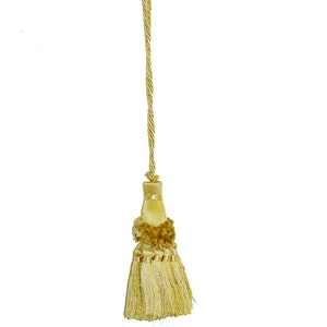 May include: A gold tassel with a long cord. The tassel has a layered design with a small brown pom-pom at the top.