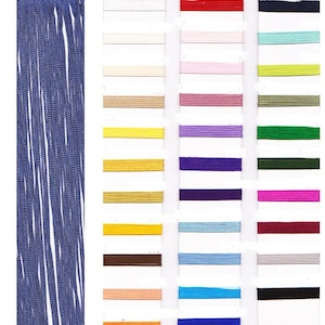 Può includere: Primo piano di una frangia blu e una tabella colori di vari nastri. La frangia è blu scuro con un bordo smerlato. La tabella colori mostra una gamma di colori, tra cui bianco, beige, giallo, viola e verde.