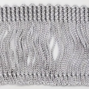 May include: Silver fringe trim with a woven design. The fringe is approximately 1 inch long.