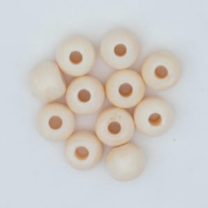May include: A collection of off-white, donut-shaped beads with a central hole. The beads are arranged on a white surface, showcasing their smooth, rounded forms. Ideal for jewelry making or craft projects.