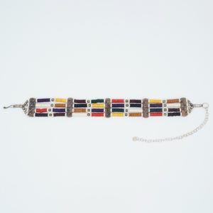 May include: A multi-strand beaded choker necklace with a variety of colorful beads. The necklace features a silver-toned chain and decorative metal accents. The beads are arranged in horizontal rows of red, black, yellow, and white.