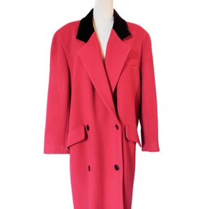 May include: A long, double-breasted red coat with a black velvet collar. The coat has two rows of black buttons, two front pockets, and a tailored fit. The coat is displayed on a mannequin.