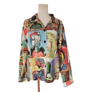 May include: A long-sleeved button-down shirt featuring a vibrant, multi-colored abstract print with various stylized human faces and geometric shapes in shades of blue, red, yellow, and green. The shirt has a classic collar and dark buttons.